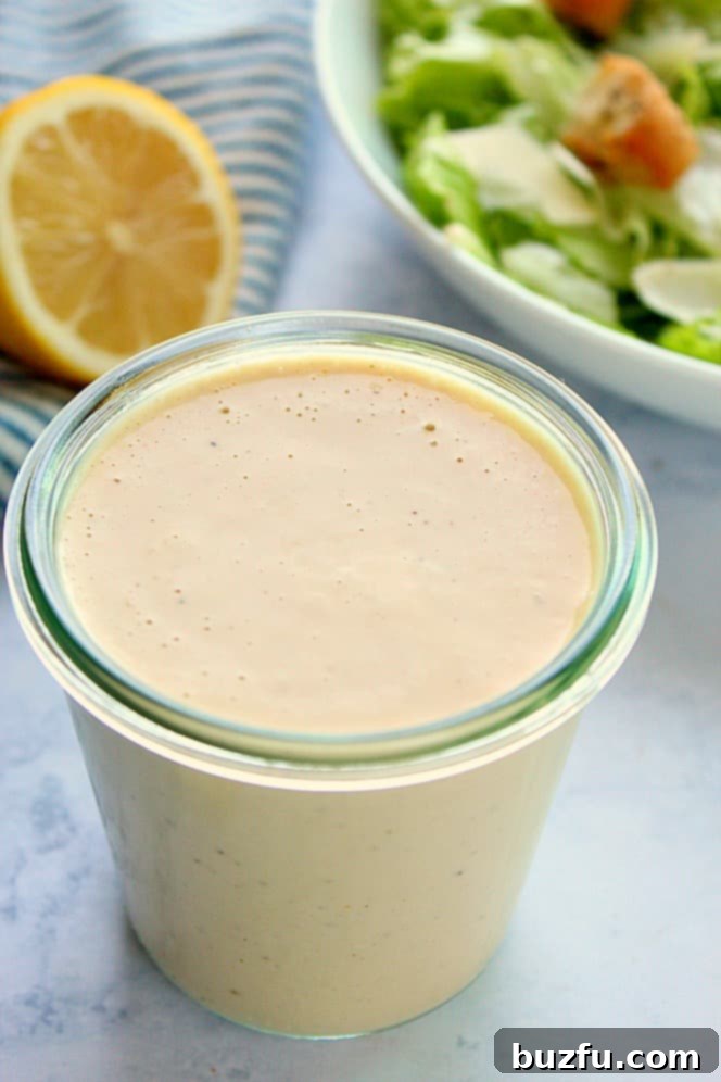 Homemade Creamy Caesar Dressing in a medium glass jar, ready to be served with a fresh salad.