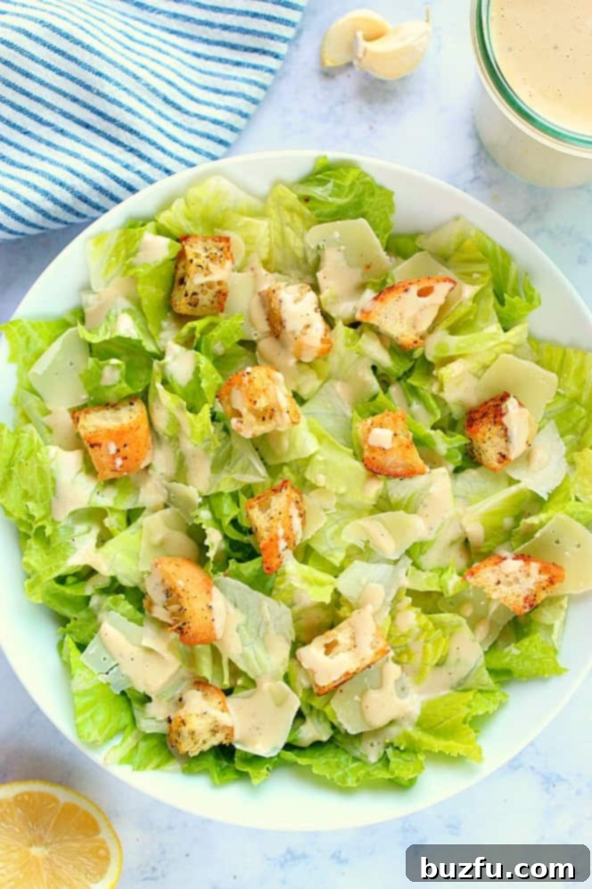 Overhead shot of Caesar salad with croutons on white salad bowl. Freshly made Caesar salad ready to be served.