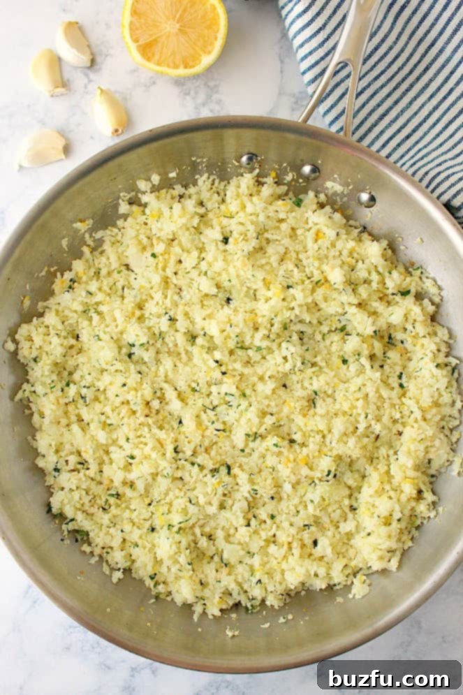 Cauliflower rice with lemon and garlic makes for a perfect low-carb side dish. Overhead shot of lemon garlic cauliflower rice in stainless steel pan.