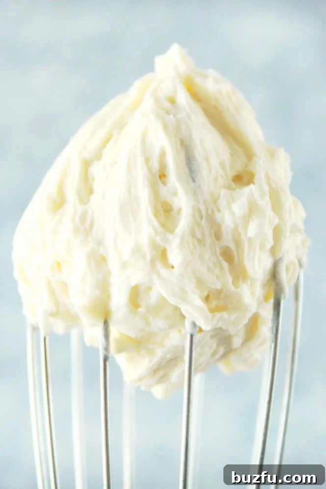 The secret to the best vanilla frosting starts with perfectly creamed butter. Close up shot of white frosting on a whisk, showcasing its fluffy texture.
