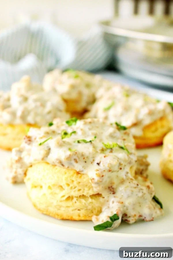 Best Homemade Sausage Gravy - A classic Midwestern and Southern breakfast, perfect for Biscuits and Gravy! Golden-brown biscuits on a plate generously covered with a thick, creamy sausage gravy.