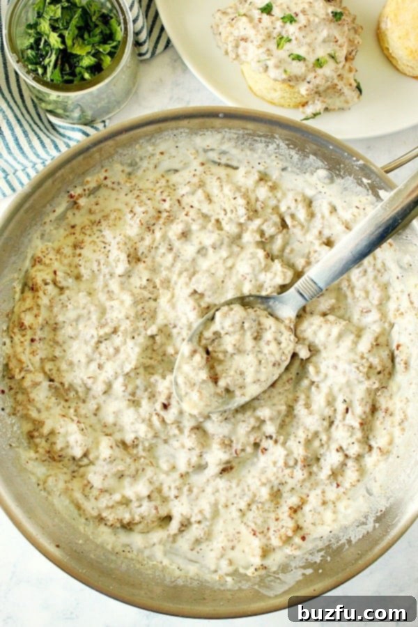 How to make perfect sausage gravy from scratch using ground pork sausage, milk, and cornstarch for a rich, smooth texture. Close-up overhead shot of bubbling, creamy sausage gravy in a stainless steel skillet, ready to be served.