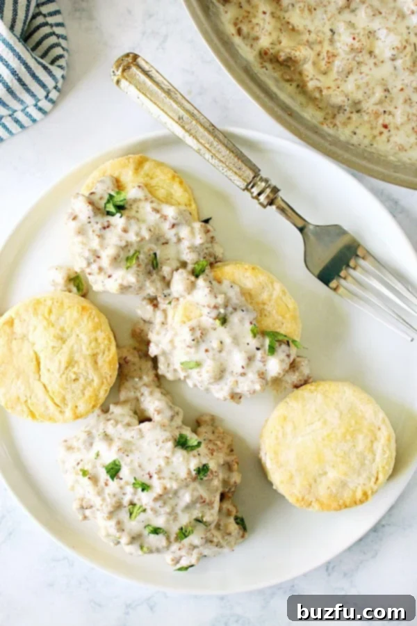 Homemade Best Sausage Gravy, a rich and filling Midwestern and Southern breakfast, perfectly paired with biscuits. Overhead shot of a plate with several golden-brown biscuits, some generously covered in creamy, savory sausage gravy.