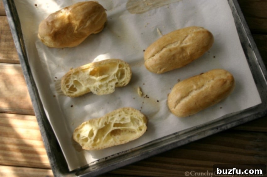 Overhead shot of freshly baked eclair pastries cooling on a baking sheet, ready for filling.