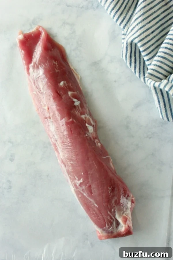 Distinguishing Pork Loin from Pork Tenderloin for Cooking Overhead shot of raw pork tenderloin on marble, showing its lean, elongated shape.