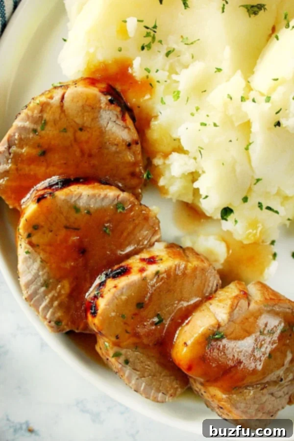 Serving Suggestion: Instant Pot Pork Tenderloin with Mashed Potatoes Overhead shot of pork tenderloin slices next to mashed potatoes on a plate, drenched in gravy.