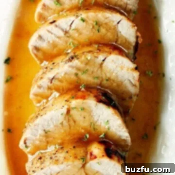 Effortless Instant Pot Pork Tenderloin 3 Slices of pork tenderloin in gravy in oval dish.