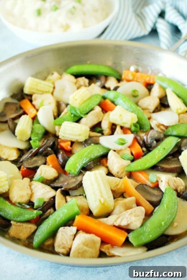 Moo Goo Gai Pan in a gleaming stainless steel pan, showcasing tender chicken, mushrooms, and vibrant vegetables.
