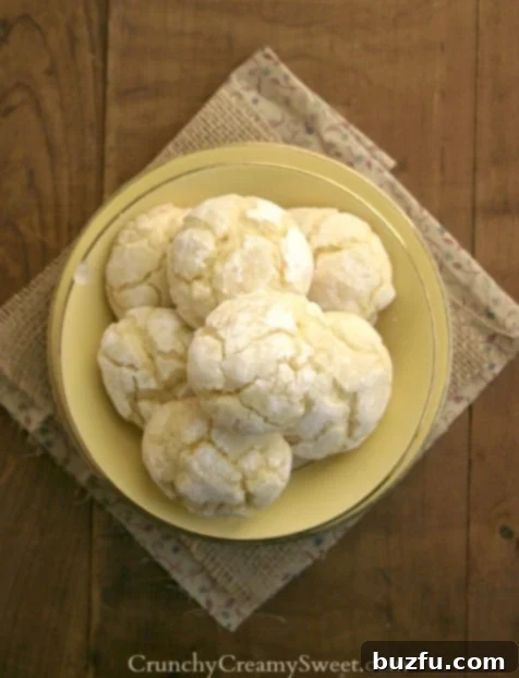 Overhead shot of yellow plate with lemon cookies on wooden background. Fresh lemons in the background.