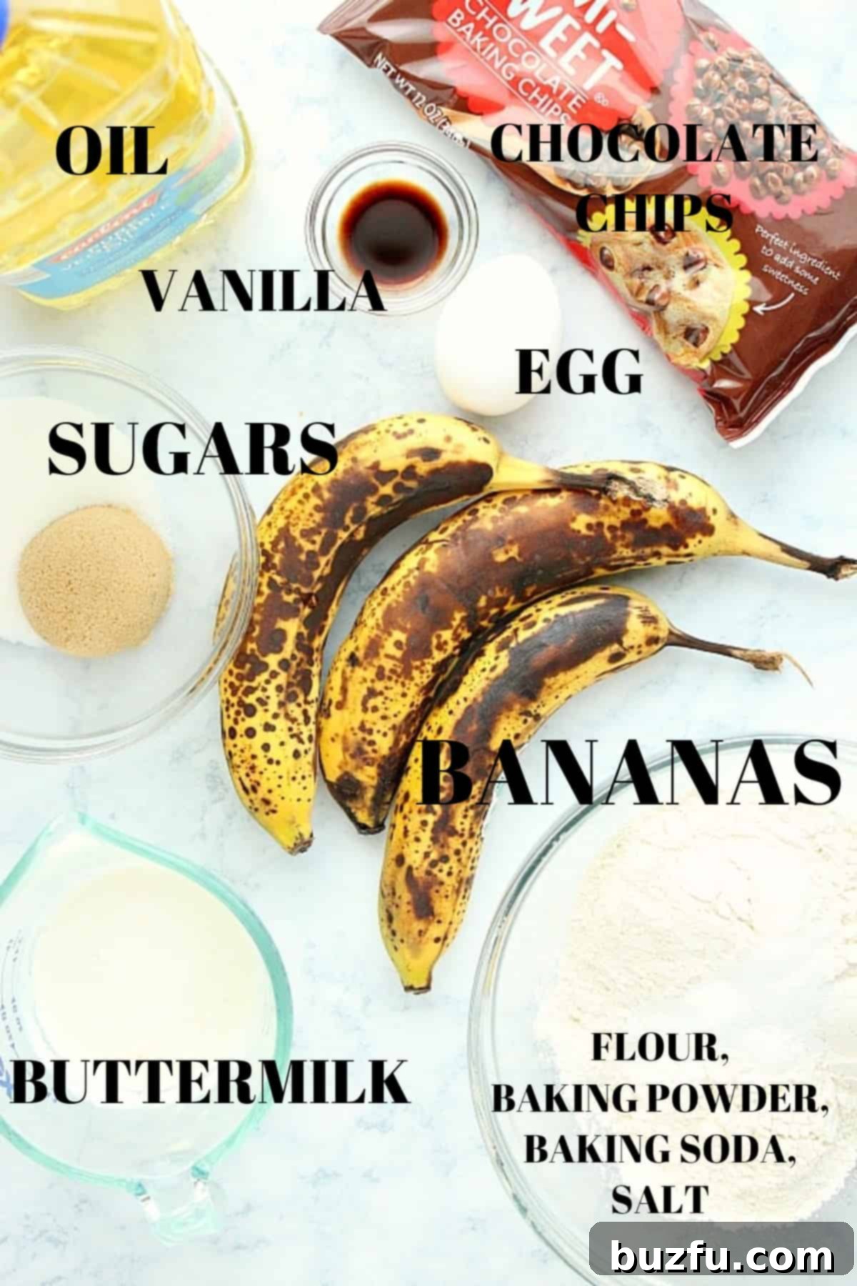 Effortless One Bowl Banana Bread 2 A flat lay photograph showcasing all the fresh and pantry ingredients needed to make homemade banana bread, neatly arranged on a pristine marble board.