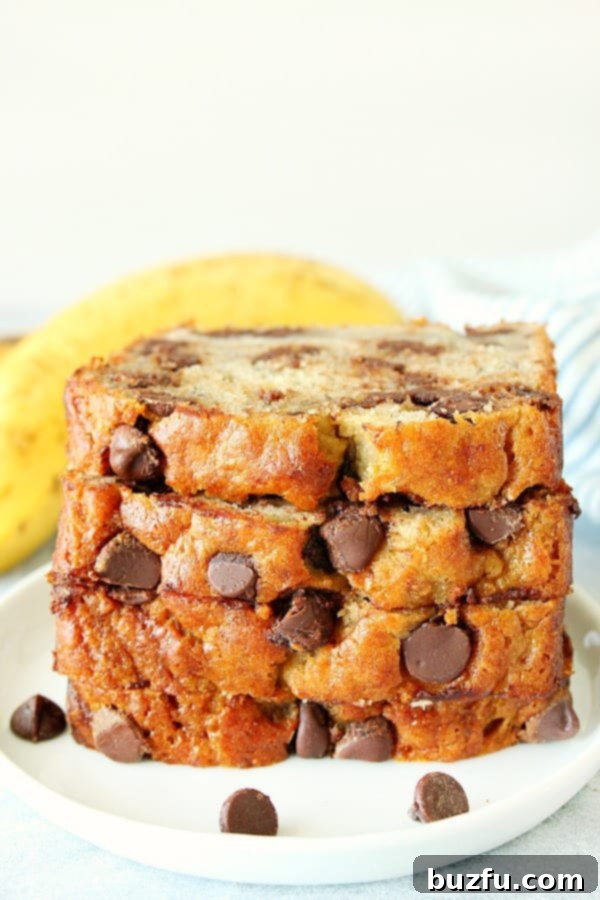 Delicious Slices of One Bowl Banana Bread with Chocolate Chips Four perfectly sliced pieces of moist chocolate chip banana bread, stacked appealingly on a simple white plate, ready to be enjoyed.