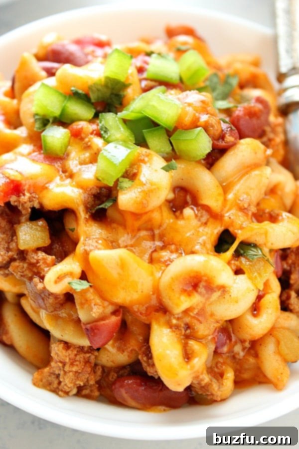 A bowl of hot Instant Pot Chili Mac with melted cheese and fresh toppings.