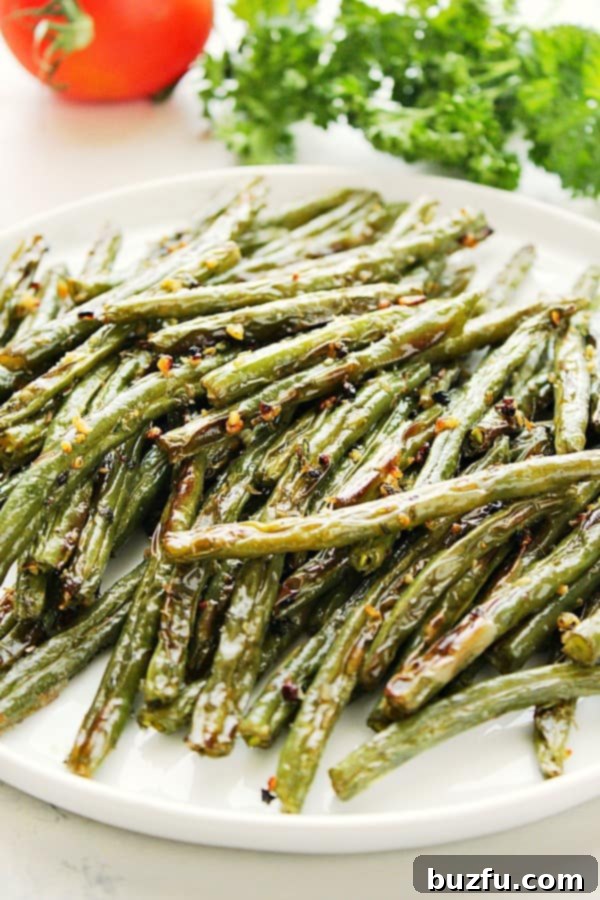 A vibrant plate of roasted green beans with fresh tomato and parsley, showcasing perfect browning.