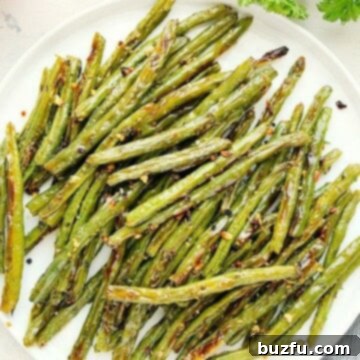 Close-up of roasted green beans on a white plate, ready to be served.