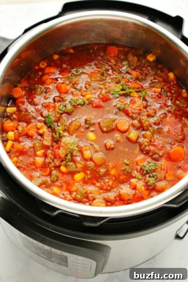 Hearty Hamburger Soup cooking in an Instant Pot pressure cooker, steam rising from the lid.