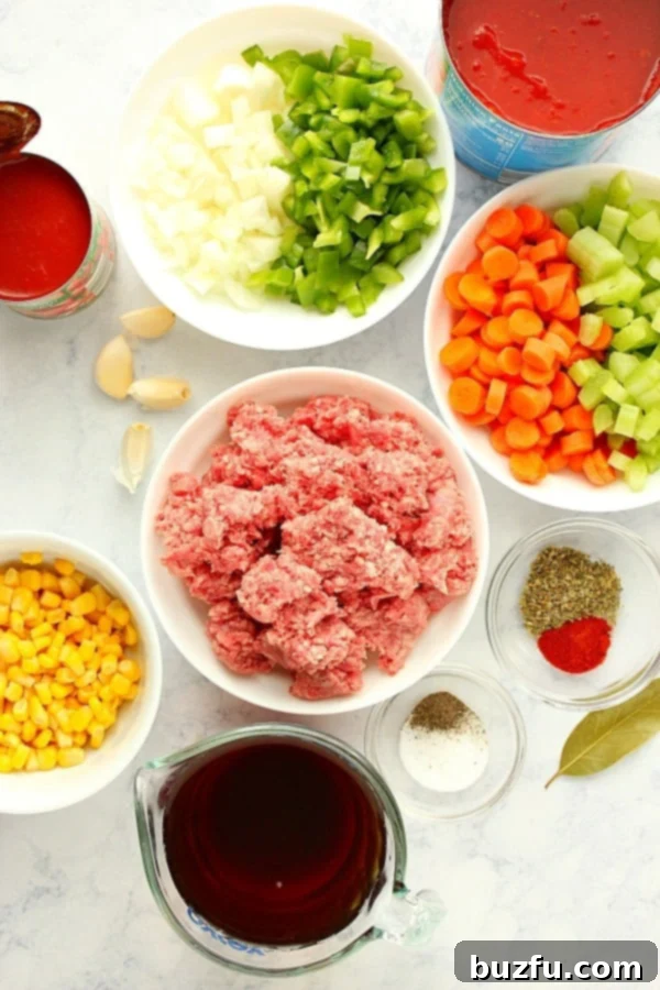 Various ingredients for Instant Pot Hamburger Soup arranged on a marble board, including ground beef, fresh vegetables, spices, and canned tomatoes.