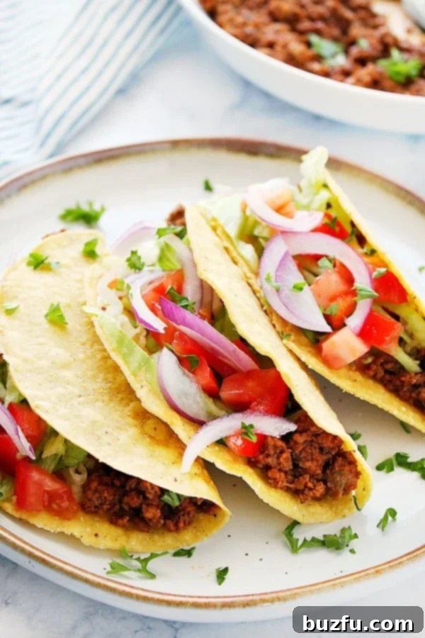 Instant Pot Taco Meat served in crispy tortilla shells on a plate with fresh toppings.