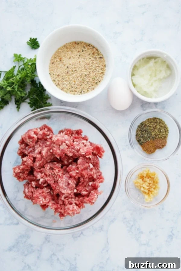Essential ingredients for crafting delicious homemade Greek Keftedes. Fresh ingredients laid out on a marble board for making Greek meatballs, including ground lamb, various herbs, and a selection of spices.