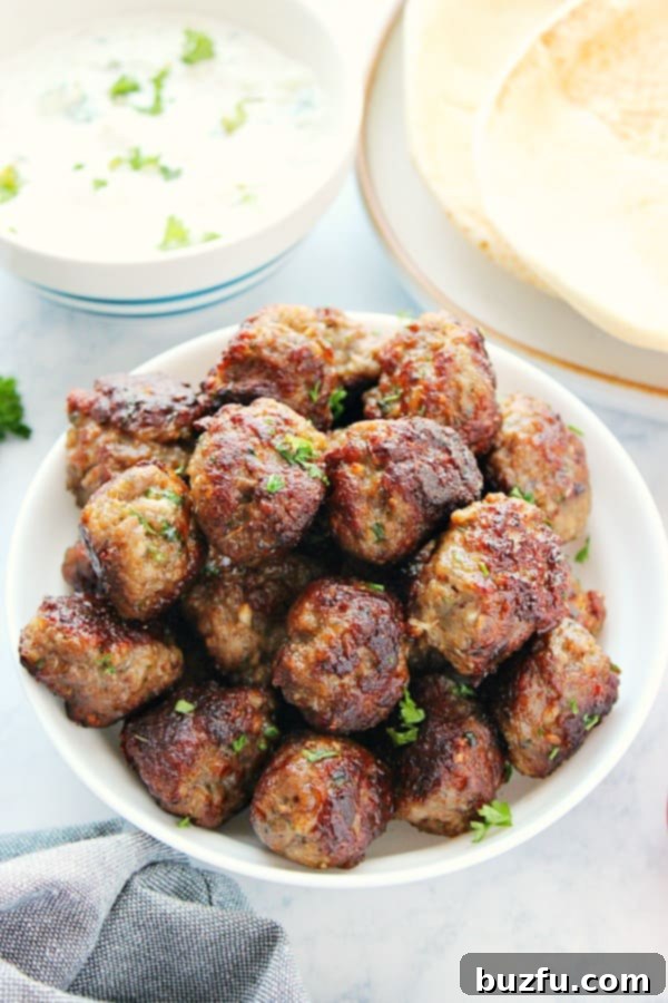 Delicious and easy Greek Meatballs, perfect for any meal. Succulent ground lamb meatballs (Keftedes) served elegantly in a bowl, garnished with fresh herbs and a drizzle of olive oil.
