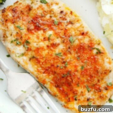 Herb-Crusted Baked Pork Chops 8 Close-up of a perfectly baked pork chop on a white plate, garnished with fresh herbs.