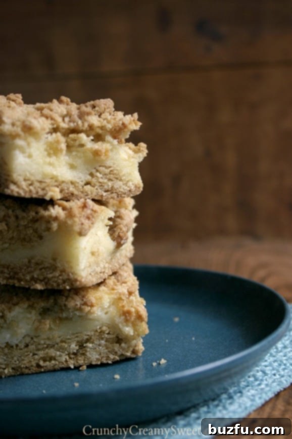Close-up of a stack of Sour Cream Crumb Bars, showcasing the distinct layers of crust, creamy filling, and crumb topping.