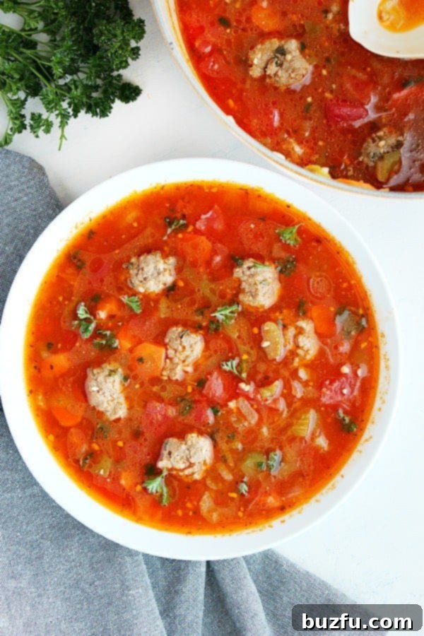 A steaming bowl of vibrant Albondigas soup garnished with fresh cilantro and lime.