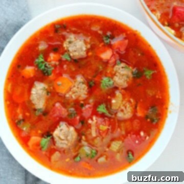 Albondigas Soup in a white bowl, garnished with cilantro and lime.