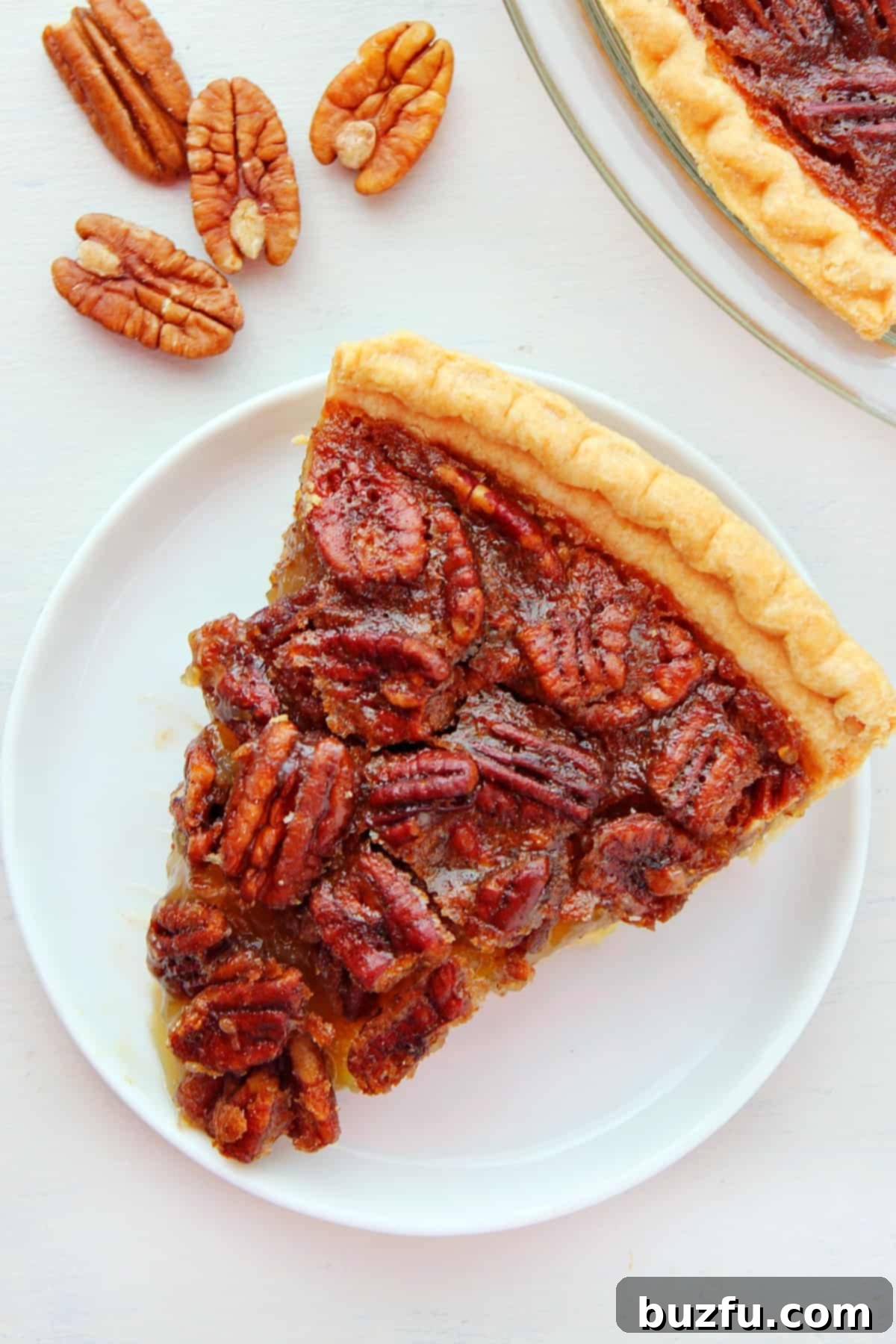 The easiest and most decadent Pecan Pie you'll ever bake, perfect for holiday gatherings. A perfectly baked slice of Pecan Pie, showcasing its rich, golden-brown filling and crunchy pecan topping, served on a pristine white plate.