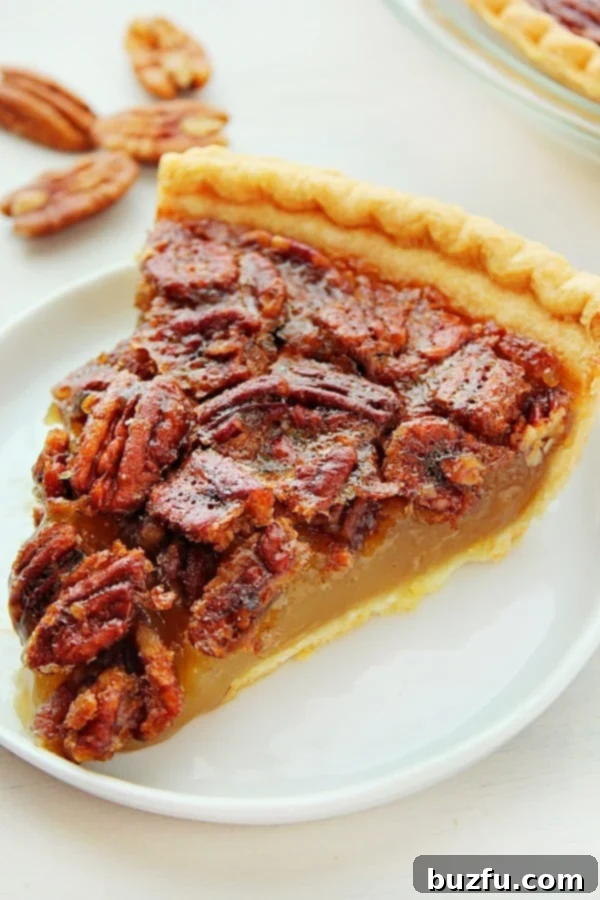 Learn how to effortlessly bake an incredibly easy and delicious Pecan Pie. A delectable slice of Pecan Pie, artfully presented on a white plate with a fork, ready to be enjoyed.