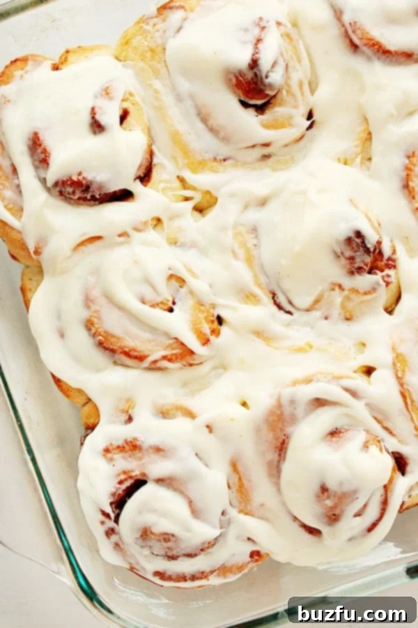 These Easy Cinnamon Rolls are soft, fluffy, have the best cinnamon filling and cream cheese frosting. Beautifully baked cinnamon rolls in a clear glass baking dish, ready to be frosted.