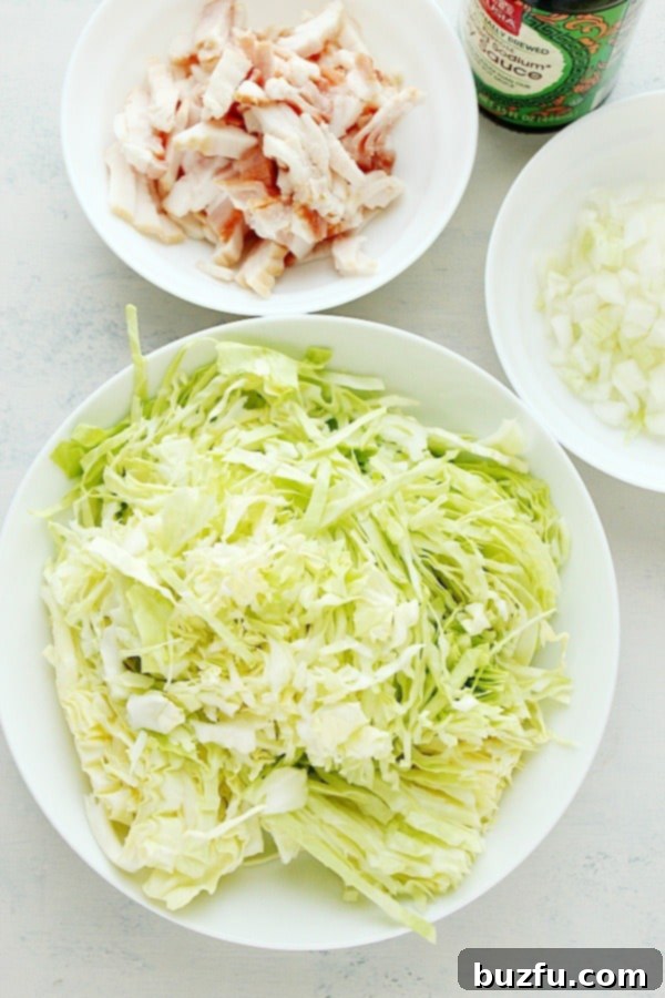 All ingredients for Fried Cabbage with Bacon displayed on a white cutting board.