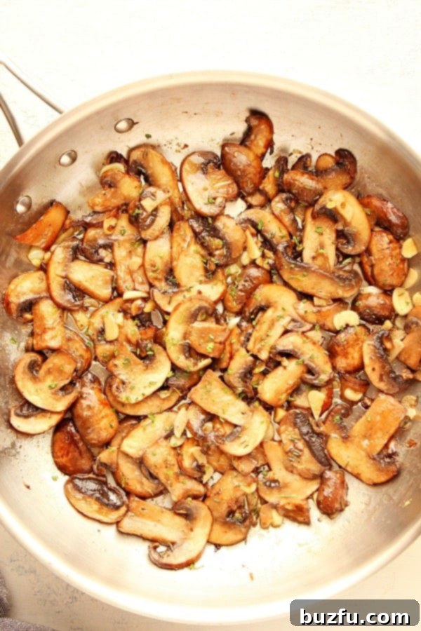 Sauteed Mushrooms glistening in a pan, infused with garlic butter and herbs.