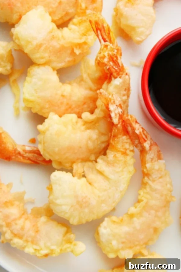 Shrimp Tempura on a white plate with a side of dipping sauce.
