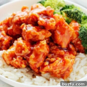 Crispy Korean chicken on rice in a bowl, garnished with sesame seeds and green onions.