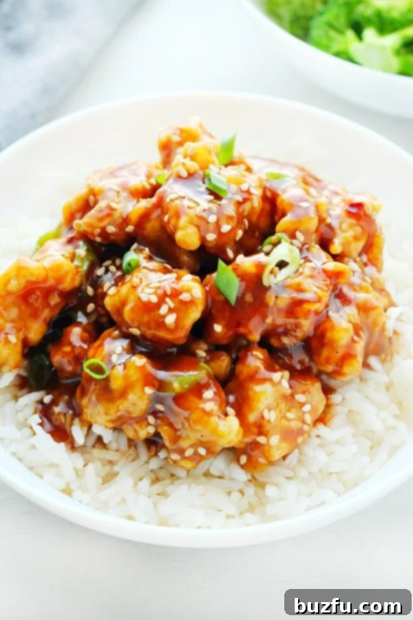 Homemade General Tso's Chicken Recipe A bowl of homemade General Tso's Chicken served over white rice, garnished with green onions.