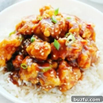 Sweet Heat Crispy Chicken 3 General Tso's chicken on rice in a bowl, garnished with fresh herbs.
