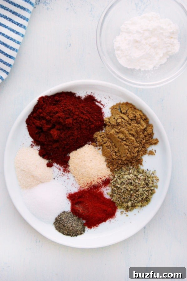 Taco Seasoning Ingredients Display Various spices for taco seasoning neatly arranged on a white plate, showcasing the vibrant colors of chili powder, cumin, paprika, and more.
