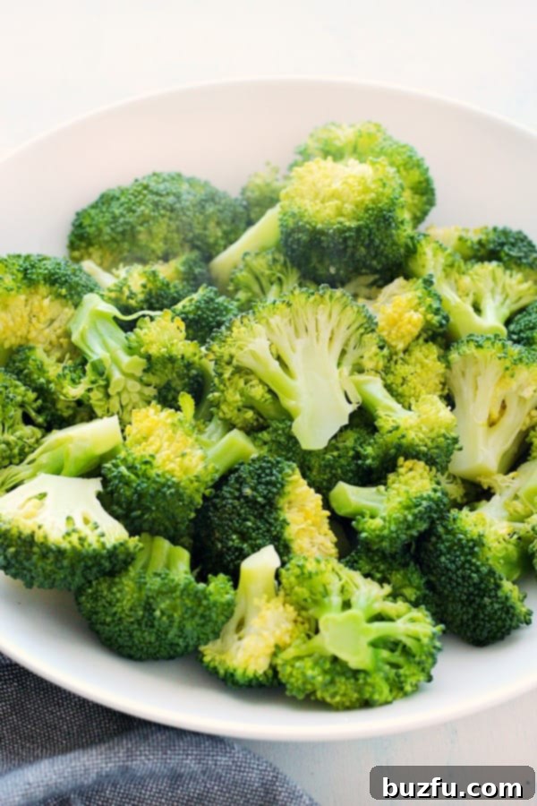 Steamed broccoli in a white bowl, garnished lightly.