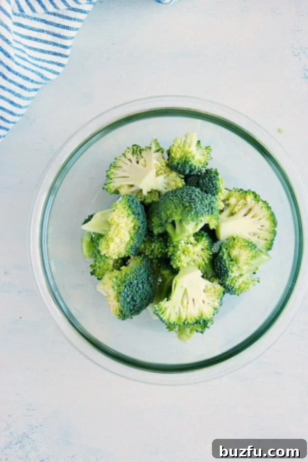 Broccoli florets in a microwave-safe bowl with a small amount of water.
