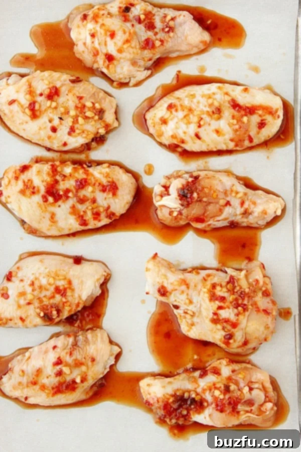 Chicken wings with sauce on baking sheet.