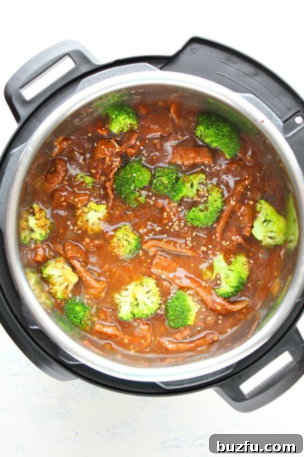 Instant Pot Beef and Broccoli served in a white bowl with rice, garnished with sesame seeds and green onions.