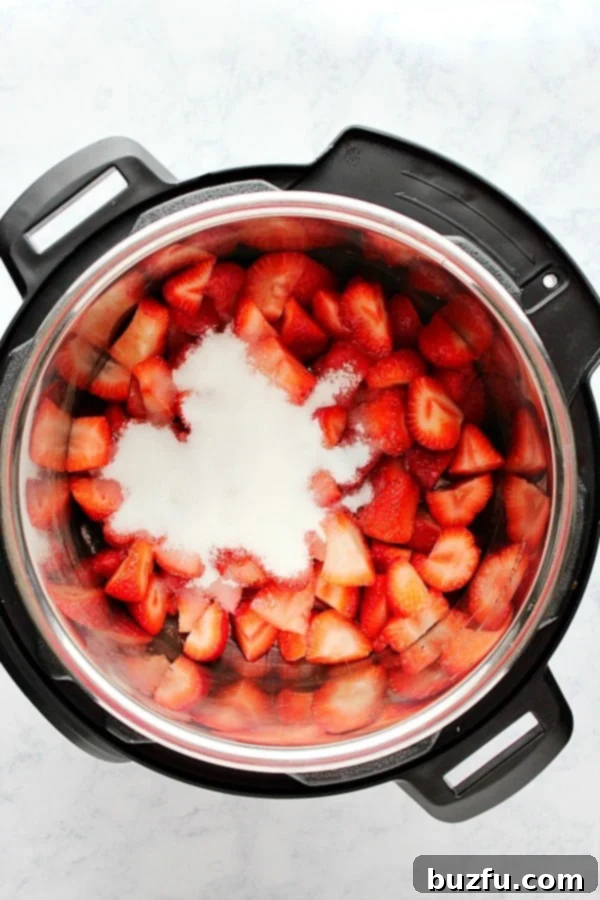 How to make strawberry jam in the Instant Pot. Chopped strawberries with sugar in pressure cooker, ready for cooking.