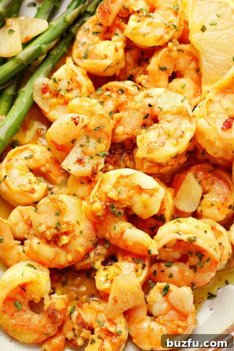 Close up photo of garlic butter shrimp on a plate with asparagus.
