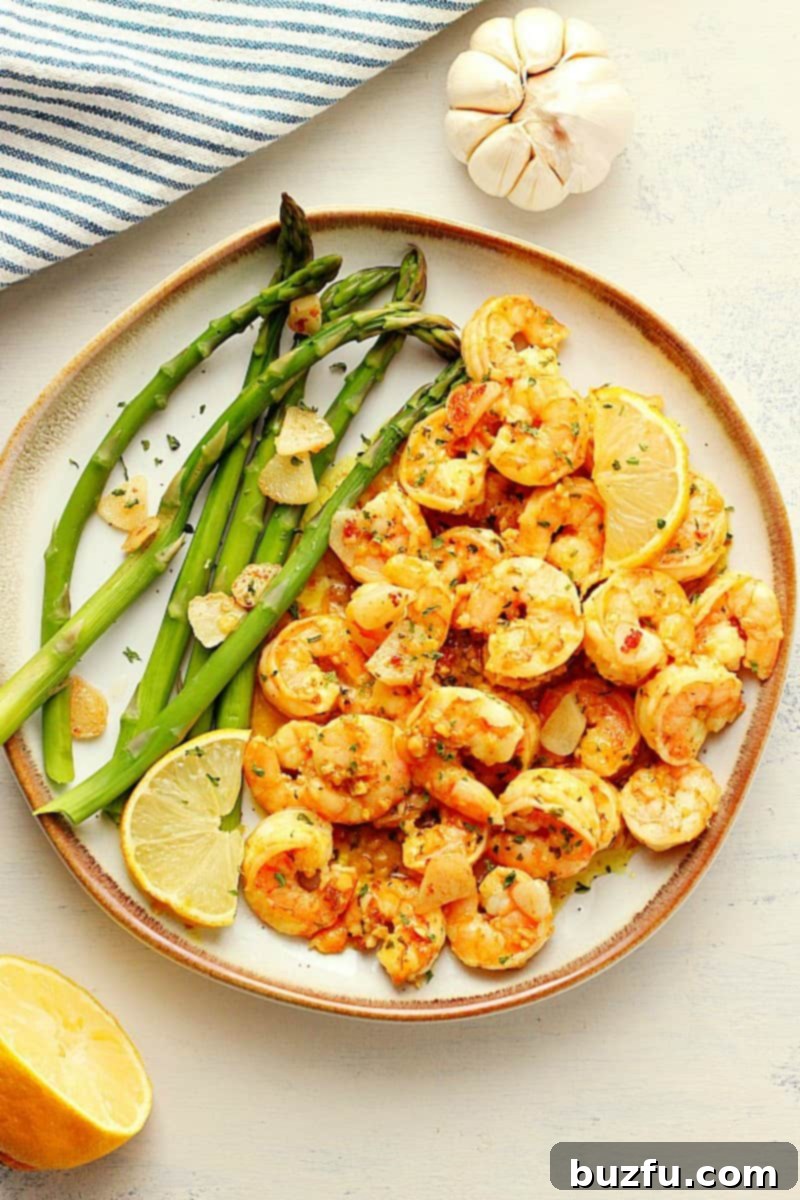 Shrimp in garlic butter and asparagus on plate with brown rim.