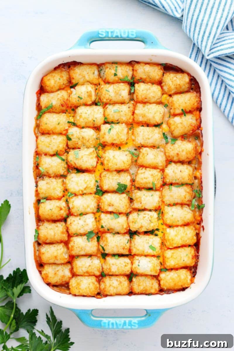 Tater tot casserole in a baking dish on white board.