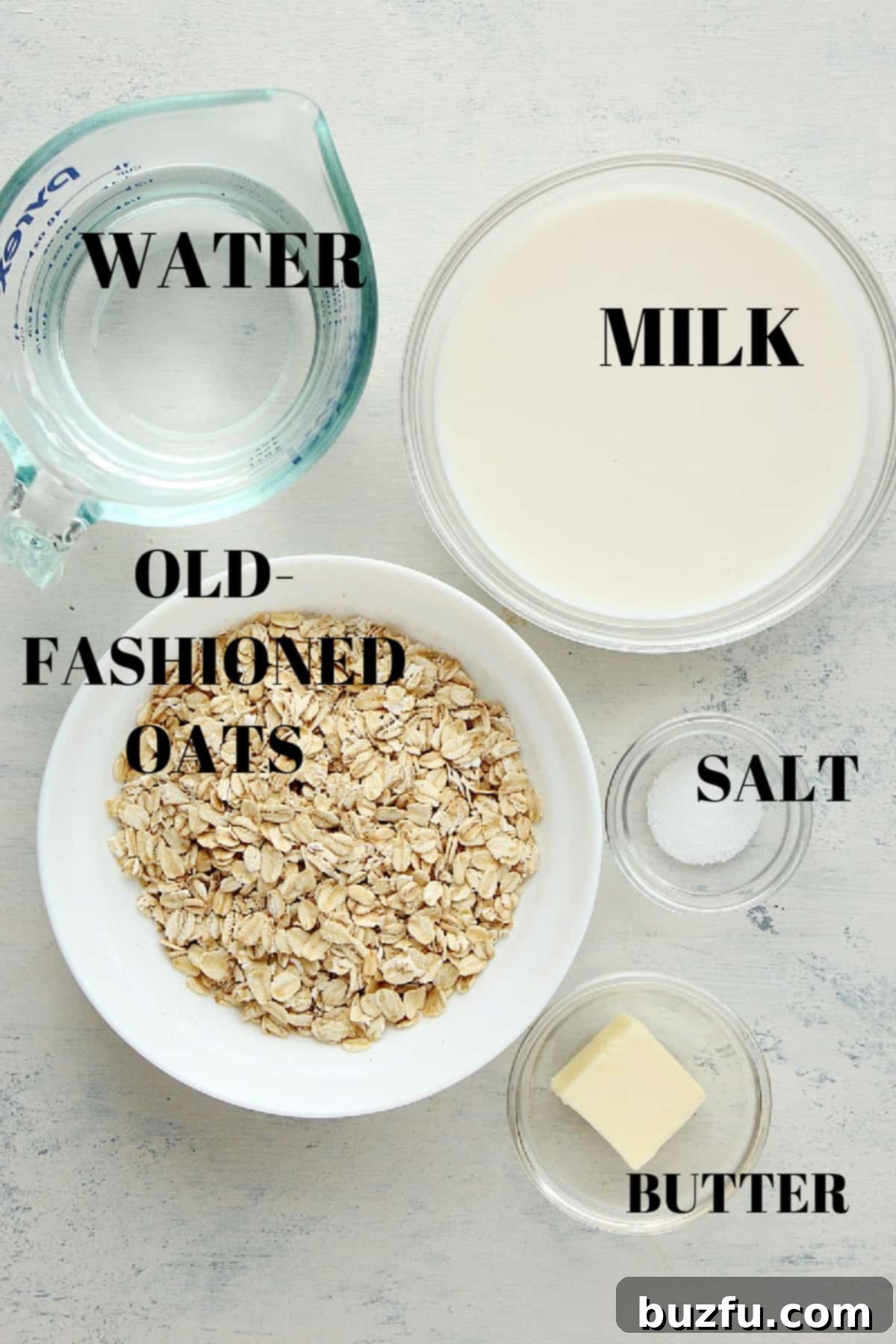 Oats, milk, water, salt and butter in small bowls, on a gray background.