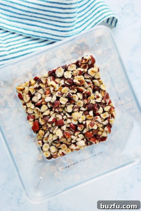 How to perfectly roast hazelnuts for the best homemade chocolate hazelnut spread. Perfectly toasted hazelnuts on a baking sheet, ready for making homemade Nutella.