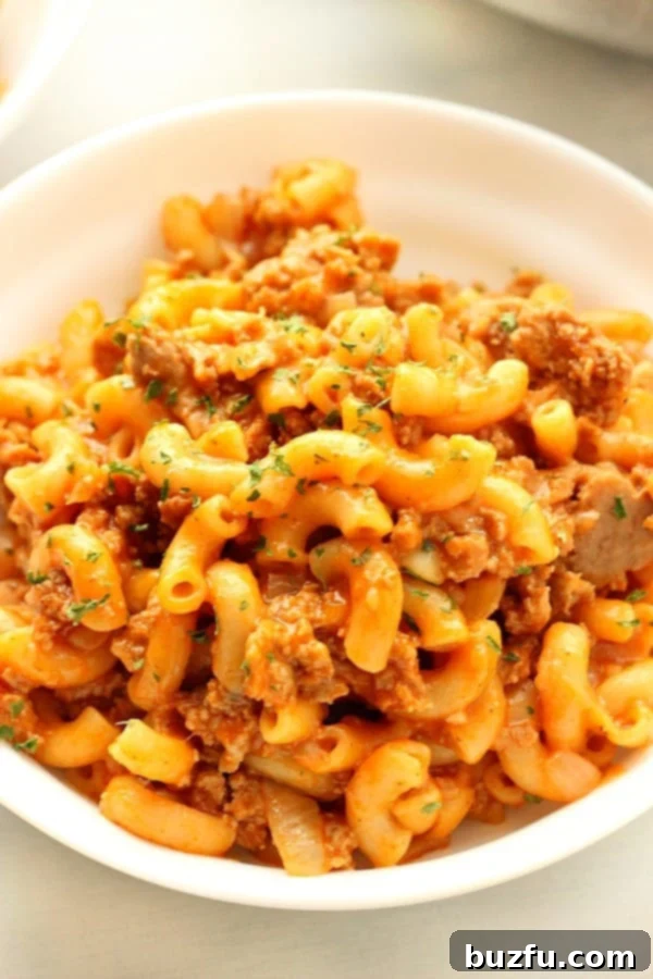 A comforting macaroni pasta casserole in a white bowl, garnished with fresh parsley.