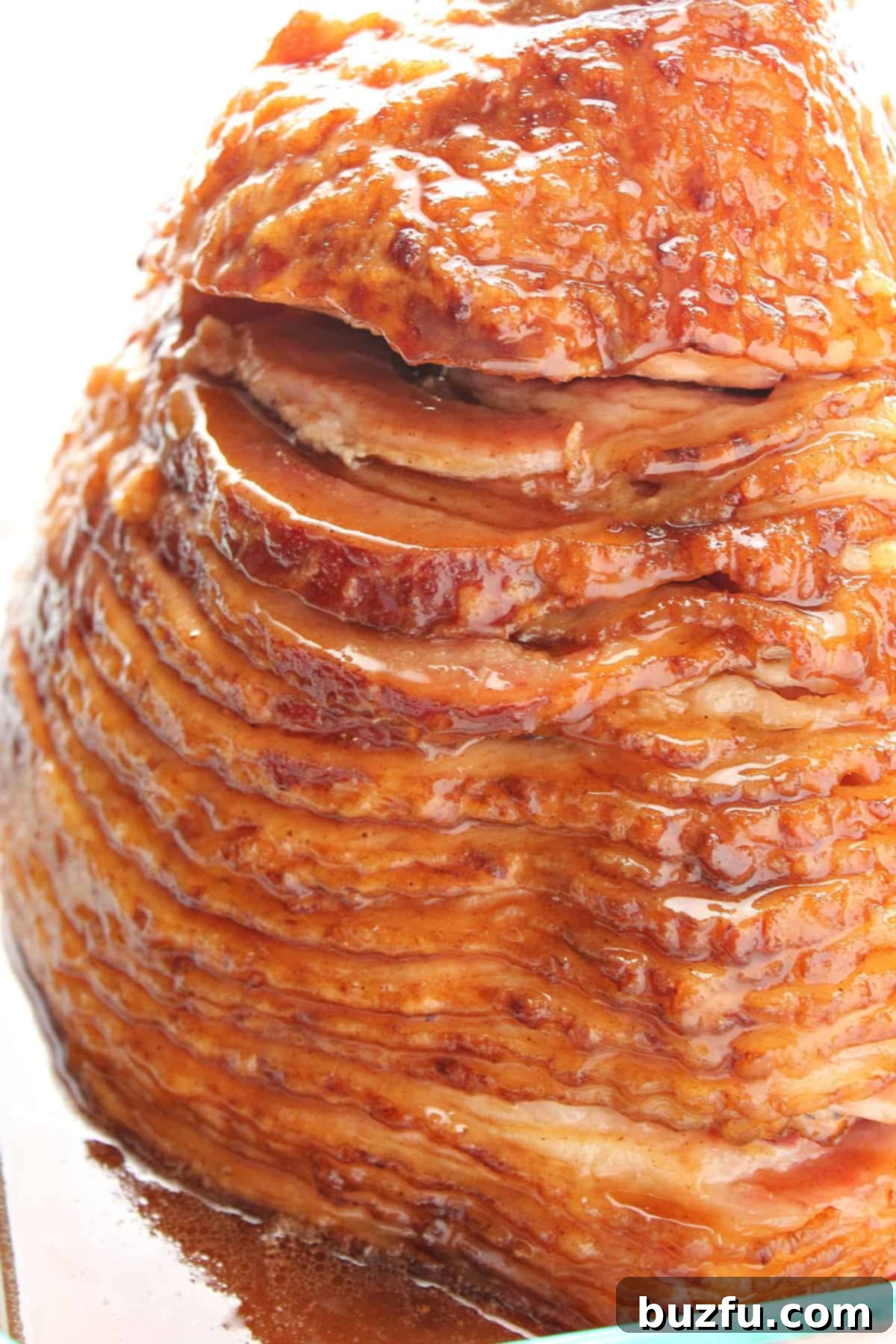Ham sliced in a baking dish, glistening with honey glaze.