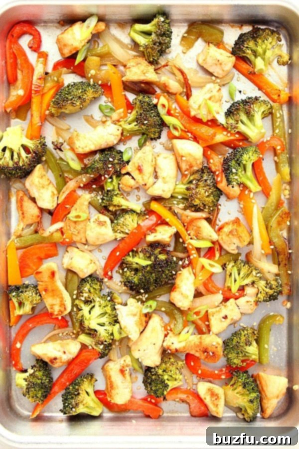 Close-up of baked chicken and colorful vegetables on a sheet pan, cooked to perfection.